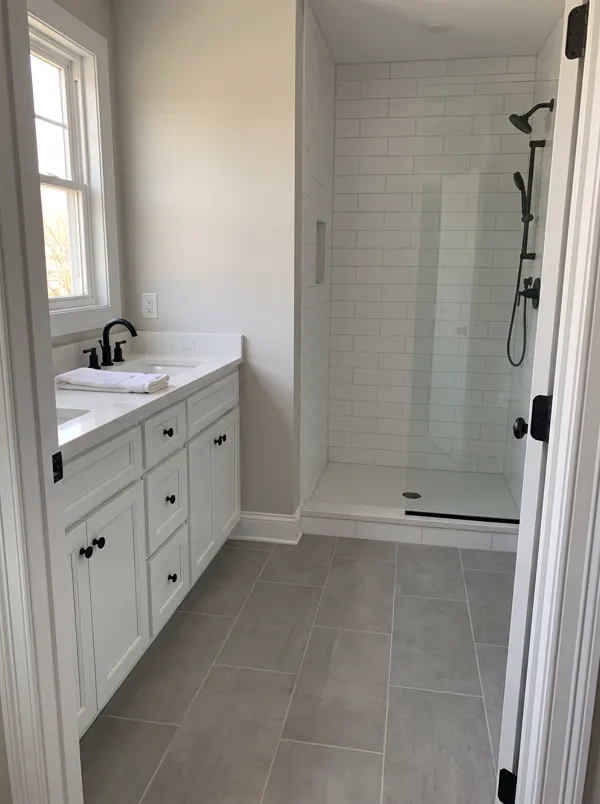 A finished bathroom remodel with a white vanity and a tiled walk-in shower